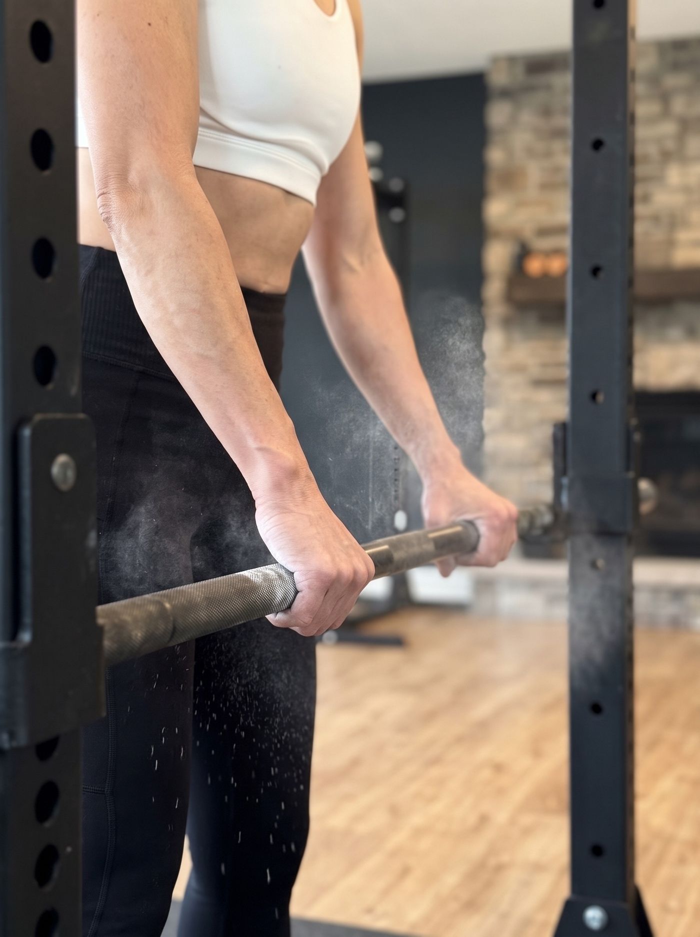 Chalked hands gripping a barbell in the Strong State studio, morning light.